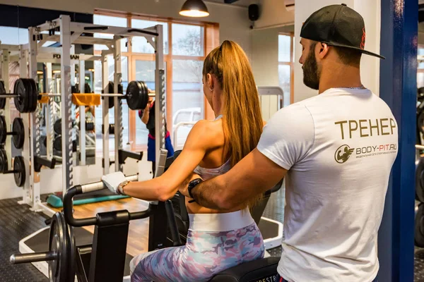 Volver ver entrenador personal coaching mujer culturista en la máquina en el gimnasio moderno — Foto de Stock