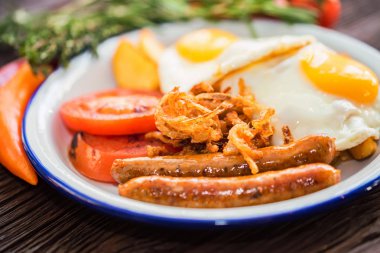 Yumurtalı, domatesli, soğan halkalı ve sosisli tipik kahvaltı.