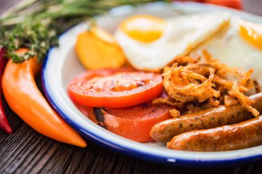 Yumurtalı, domatesli, soğan halkalı ve sosisli tipik kahvaltı.