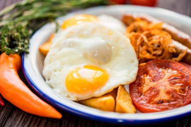 Yumurtalı, domatesli, soğan halkalı ve sosisli tipik kahvaltı.