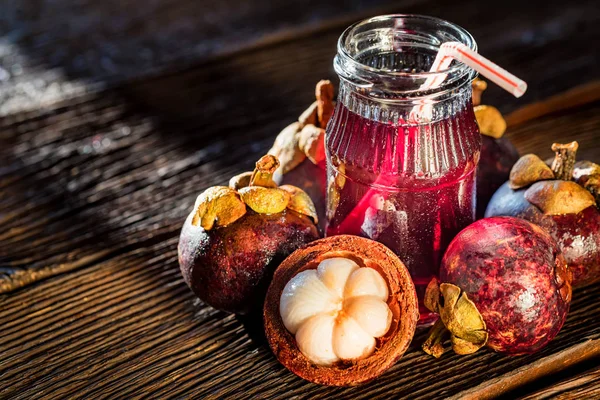 Fresh Mangosteen fruit and drink in jar on wooden background