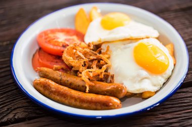 Yumurtalı, domatesli, soğan halkalı ve sosisli tipik kahvaltı.