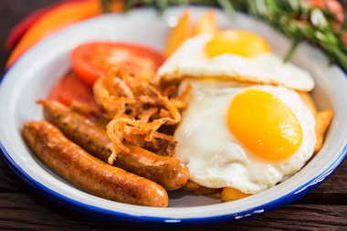 Yumurtalı, domatesli, soğan halkalı ve sosisli tipik kahvaltı.