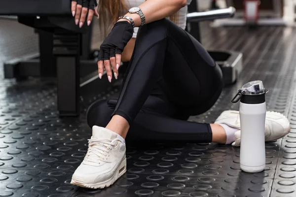 Model fitness atrakcyjne siedzi z fitness drink w nowoczesnej siłowni. Dolnej części widoku — Zdjęcie stockowe