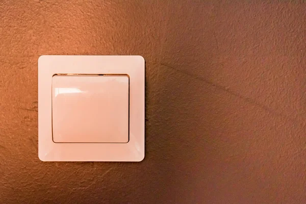 White modern light switch on beige wall close