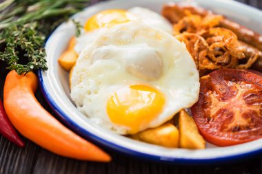 Yumurtalı, domatesli, soğan halkalı ve sosisli tipik kahvaltı.