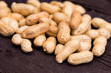 Koyu ahşap arka plan üzerinde soyulmamış fıstık yığını kapat