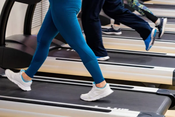 Stäng upp benen på människor på moderna löp band i gymmet. Lägre Delvy — Stockfoto