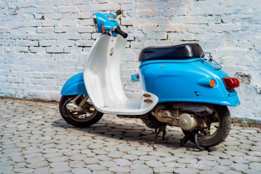 Şehrin caddesinde park etmiş mavi scooter.