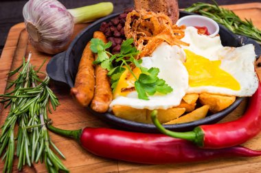 Kızarmış yumurta, sosis, fasulye, soğan halkaları, biber ve sos ile yemek