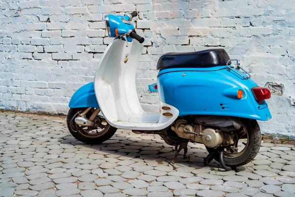 Şehrin caddesinde park etmiş mavi scooter.