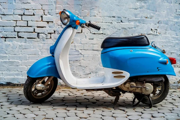 Şehrin caddesinde park etmiş mavi scooter.