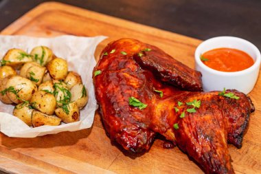 Füme tavuk uyluk ahşap tepsi yakın patates ve sos ile servis