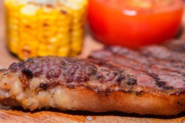 Domates ve mısır ile ahşap taze ızgara biftek kapatın
