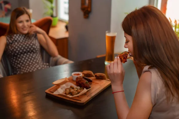 Two girl friends have lunch with beer in modern restaurant
