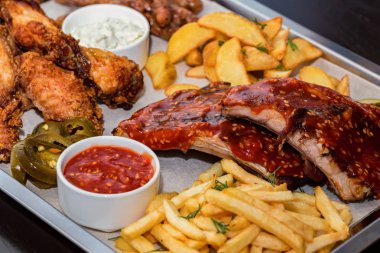 Karışık et ler. Izgara kaburga, tavuk kanadı ve patates kızartması ile sosis