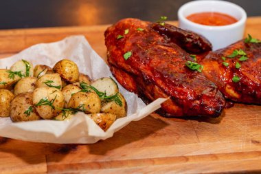 Füme tavuk uyluk ahşap tepsi yakın patates ve sos ile servis