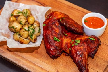 Füme tavuk uyluk ahşap tepsi yakın patates ve sos ile servis