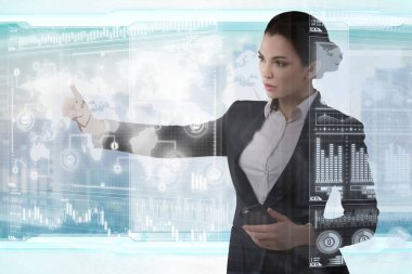 Genç iş kadını fütüristik ofiste sanal grafik arayüzü ile çalışıyor.