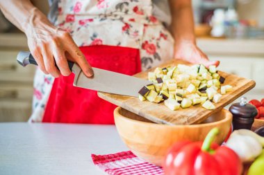 Kadın el mutfakta ahşap kase kesilmiş patlıcan koydu. Pişirme sebzeler