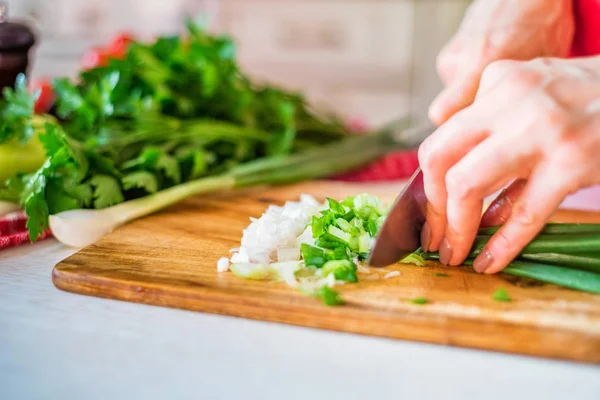 Female hand with knife cuts green leek in kitchen. Cooking vegetables — Stock Photo, Image