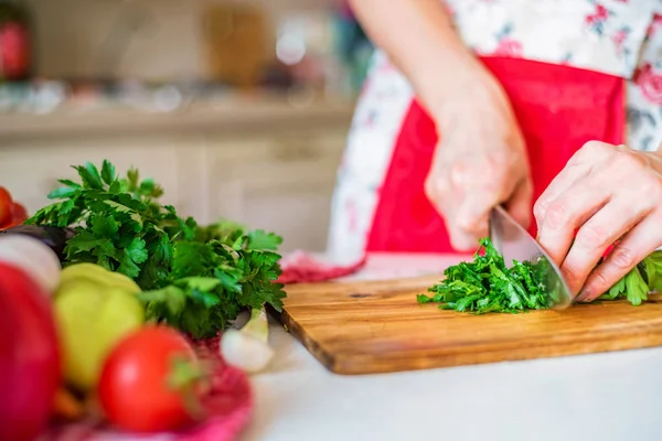 Female hand with knife cuts parsley in kitchen. Cooking vegetables — Stock Photo, Image