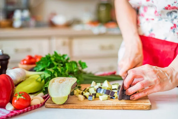 Женская рука с ножом режет баклажаны на борту на кухне. Кулинария — стоковое фото