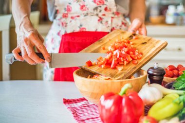 Kadın el mutfakta ahşap kase ye doğranmış biber koydu. Sebze pişirme