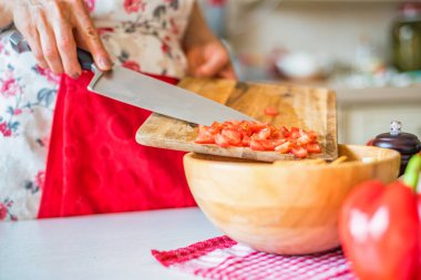 Kadın el mutfakta ahşap kase doğranmış domates koydu. Sebze pişirme