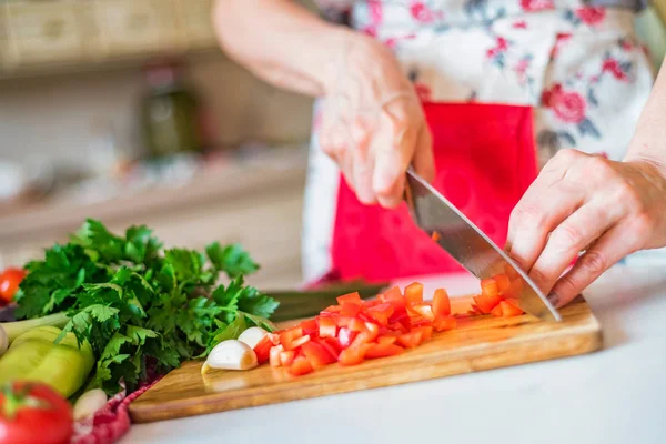 Female hand with knife chops bell pepper in kitchen. Cooking vegetables — Stock Photo, Image