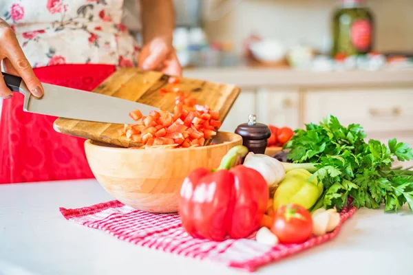 Female hand put chopped bell pepper in wooden bowl in kitchen. Cooking vegetables — Stock Photo, Image