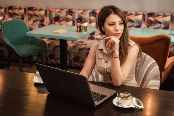 Joven hermosa mujer seria trabaja en el ordenador portátil en la cafetería — Foto de Stock