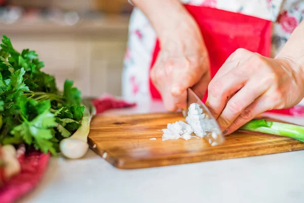 Female hand with knife cuts green leek in kitchen. Cooking vegetables — Stock Photo, Image