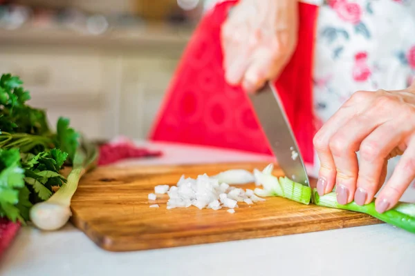 Female hand with knife cuts green leek in kitchen. Cooking vegetables — Stock Photo, Image