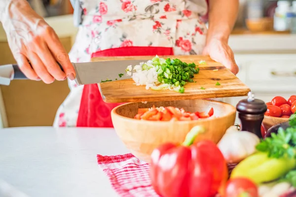 Female hand put chopped green leek in wooden bowl with salad in kitchen. Cooking vegetables — Stock Photo, Image