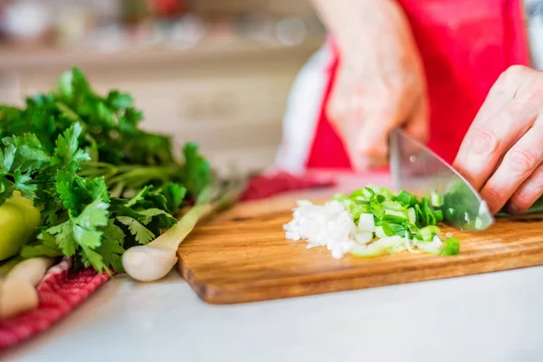 Female hand with knife cuts green leek in kitchen. Cooking vegetables — Stock Photo, Image