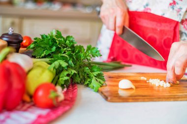 Bıçak pirzola ile kadın el mutfakta sarımsak. Pişirme sebzeler