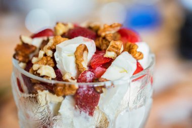 Bulanık arka planda kase de çilek ve ceviz ile Vanilyalı dondurma
