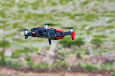 Dağlarda havada modern karanlık ve kırmızı drone yakın