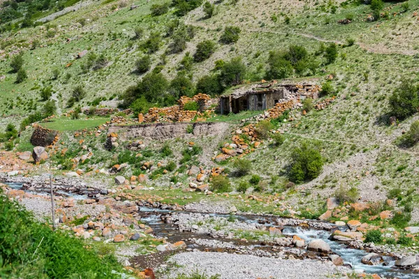 Pequeña cabaña rural de piedra y río en las montañas vista lejana — Foto de Stock