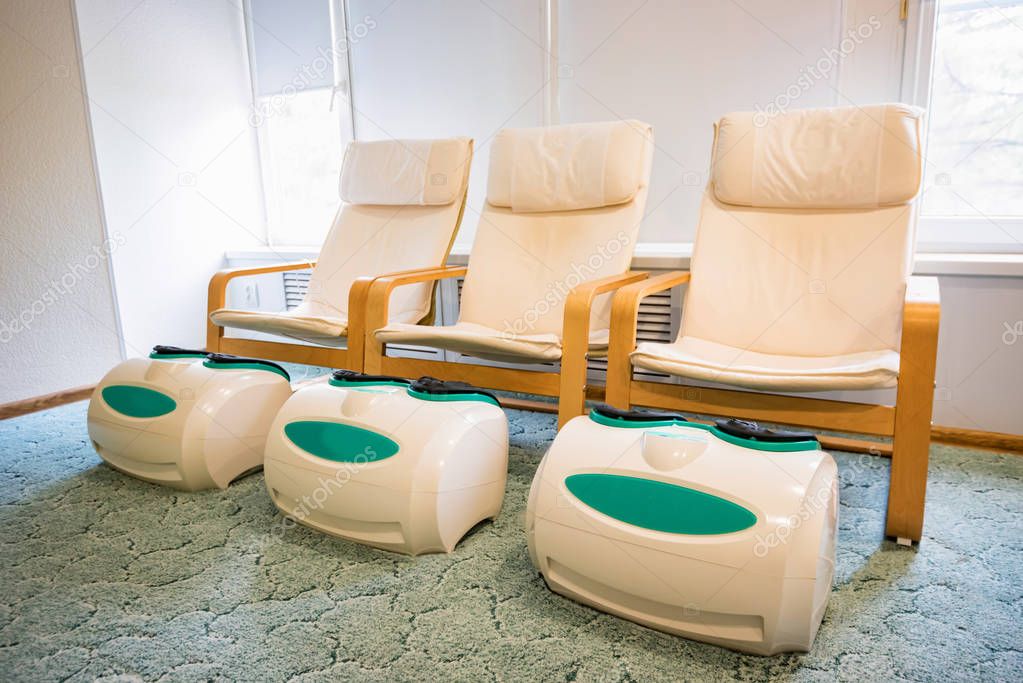 Three empty foot massage chairs in a spa cabinet