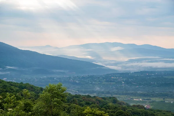 Vista panorámica de las montañas brumosas. Nubes y verde vista del bosque de montaña — Foto de Stock