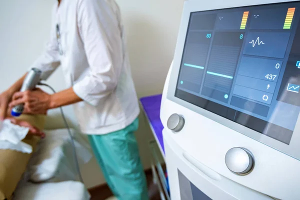 Vista do médico usando a máquina de terapia de ondas de choque radial no salão de beleza — Fotografia de Stock