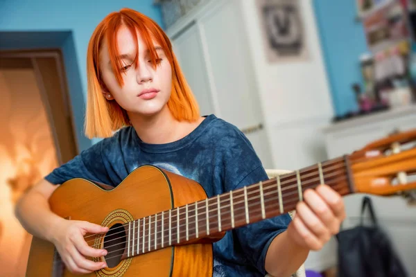 Güzel kızıl saçlı genç kız odasında gitar çalar