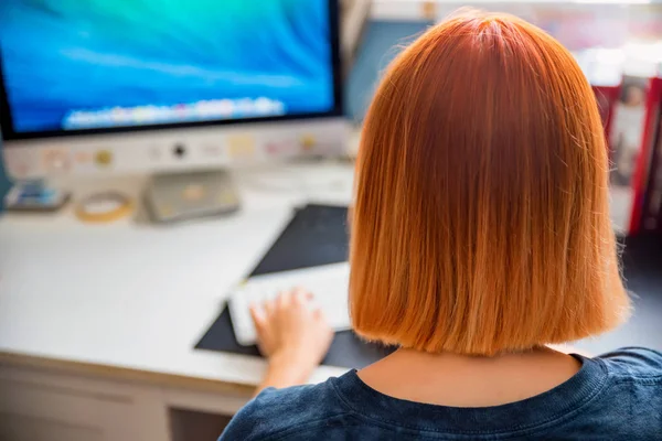 Volver ver pelirroja adolescente estudios en la computadora en su habitación — Foto de Stock