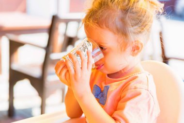 Küçük kız camdan meyve suyu içiyor.