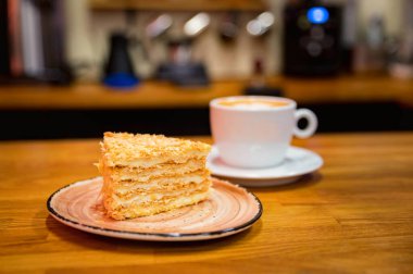 Arka planda bir fincan kahve olan vanilyalı kek. Kapuçino.