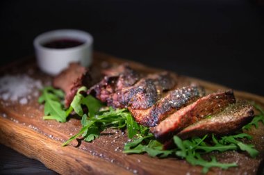 Kapalı kapılar ardında salata ile servis edilen dilimlenmiş biftek..