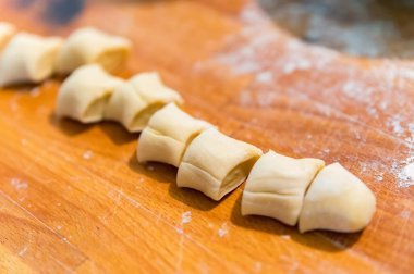 Ahşap bir tahtanın üzerinde un ile kaplanmış hamur parçalarına ayrılmış yakın plan.