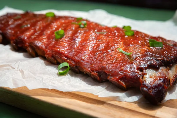 Close up board with pork ribs grilled with BBQ sauce, peanuts and jalapeno — Stock Photo, Image